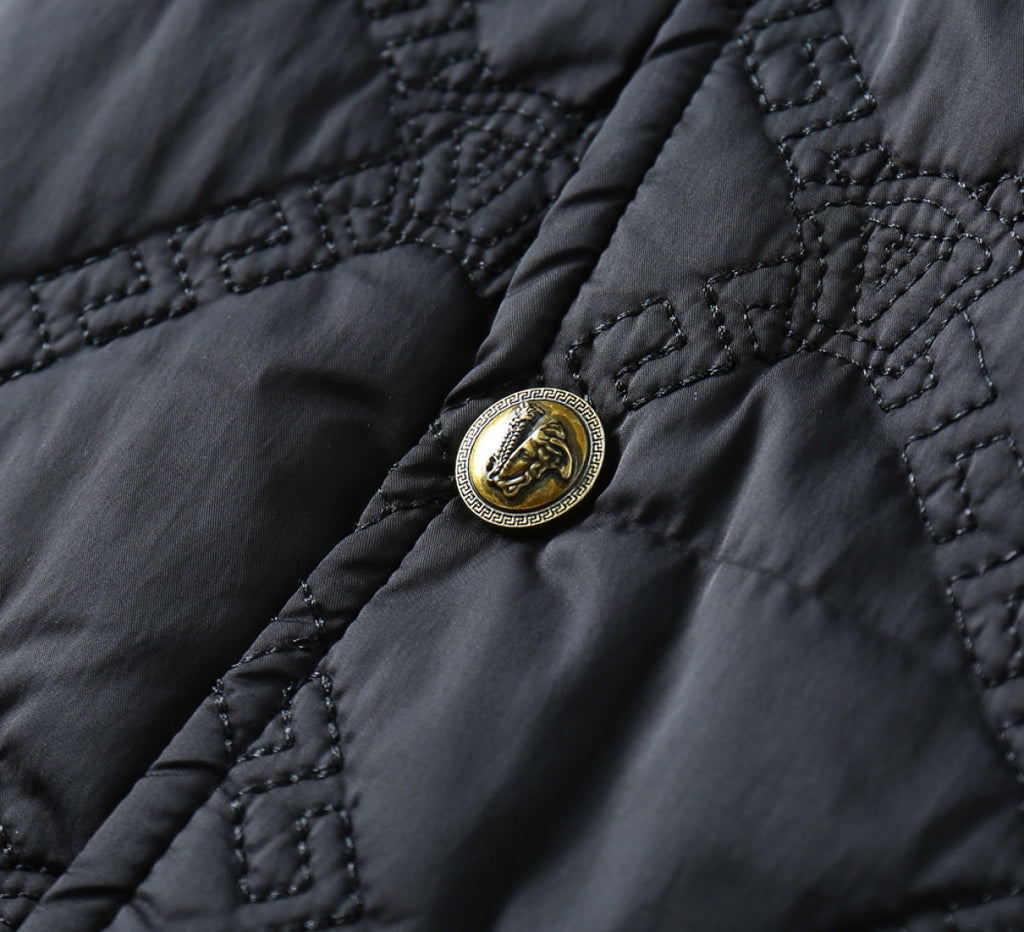 Black quilted fabric with gold emblem button detail and dark stitching