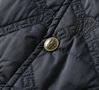 Black quilted fabric with gold emblem button detail and dark stitching