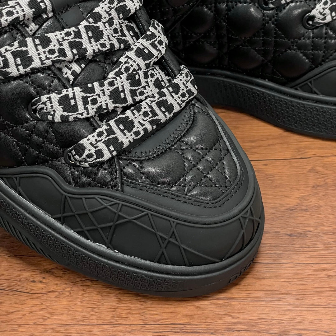 Black quilted sneakers with patterned strap and textured rubber sidewall sole