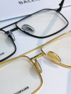 Stacked eyeglasses close-up: black and gold metal frames with clear lenses.
