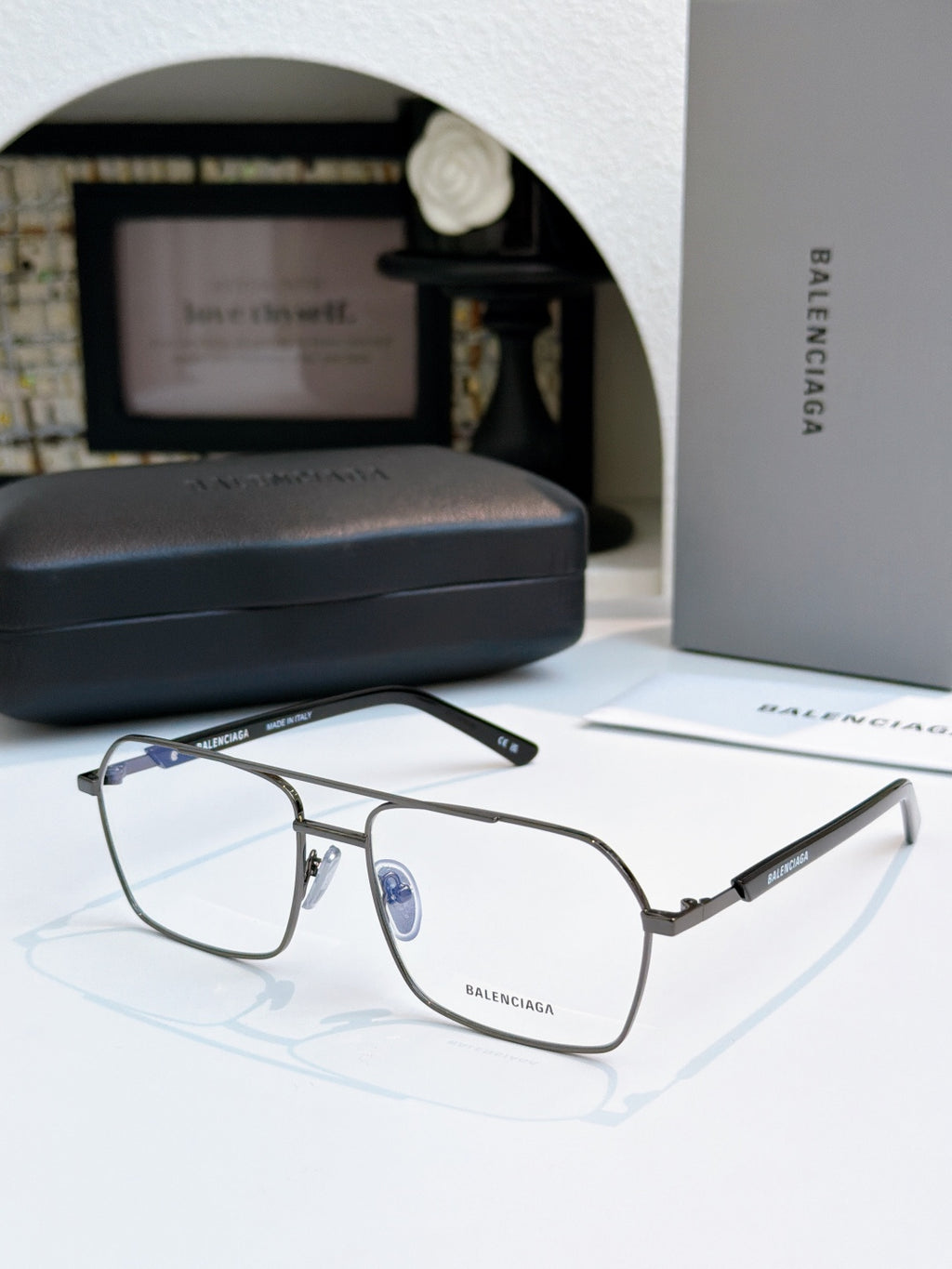 Gunmetal eyeglasses with clear lenses and blue center emblem.