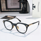 Dark blue round glasses with gold-toned details and star emblem on lens