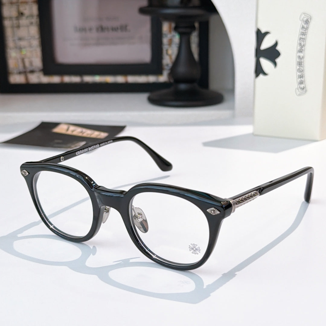 Dark blue/black round glasses with gold-toned temples and decorative arms