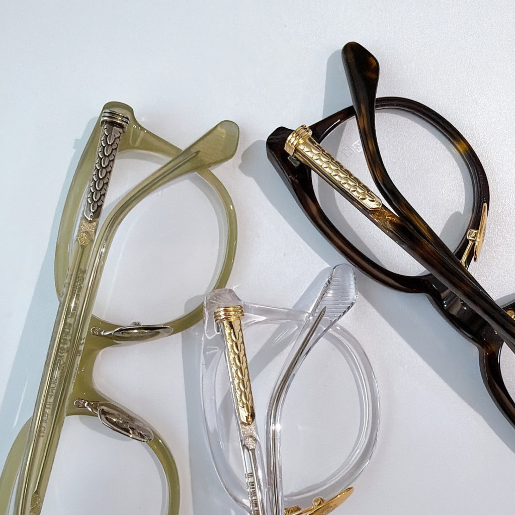 Assorted round glasses frames in clear, olive, and dark tortoiseshell with gold accents