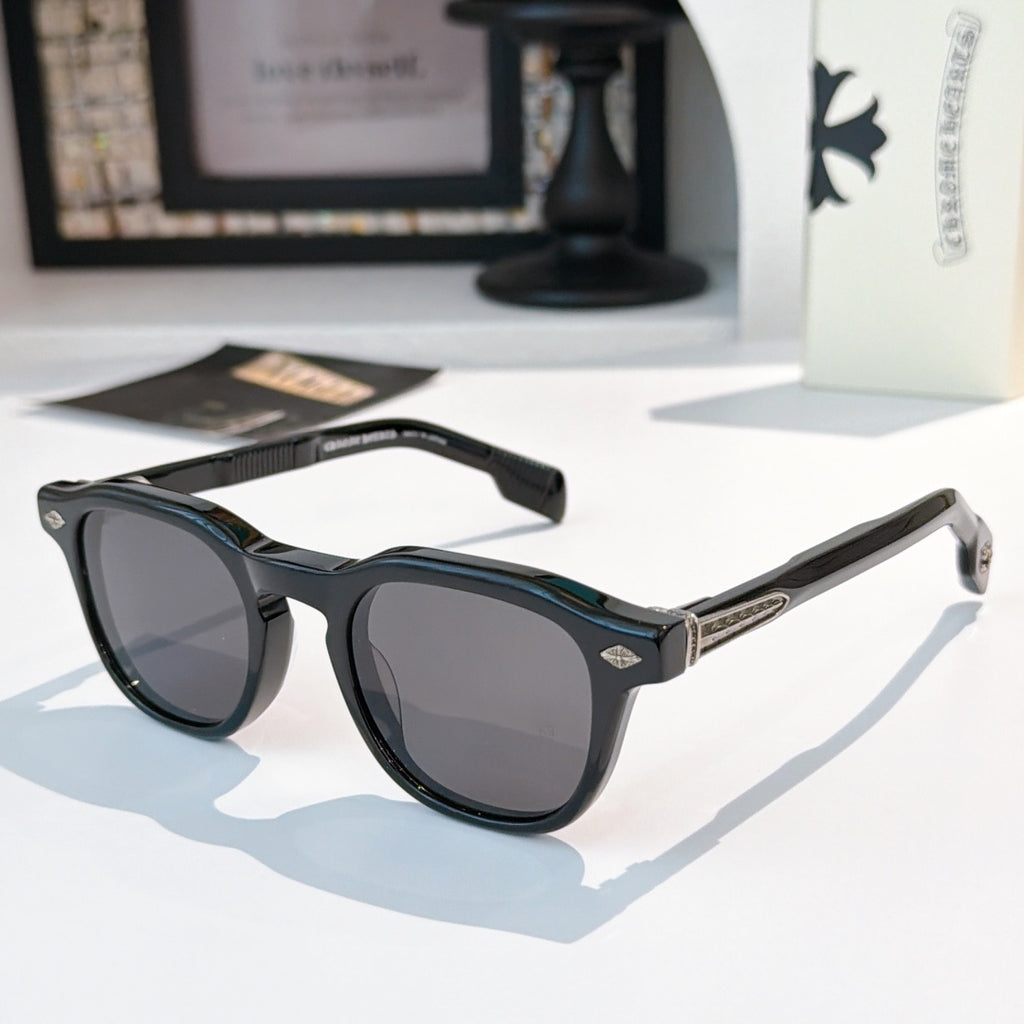 Black sunglasses with dark-tinted lenses and gold logo accents.