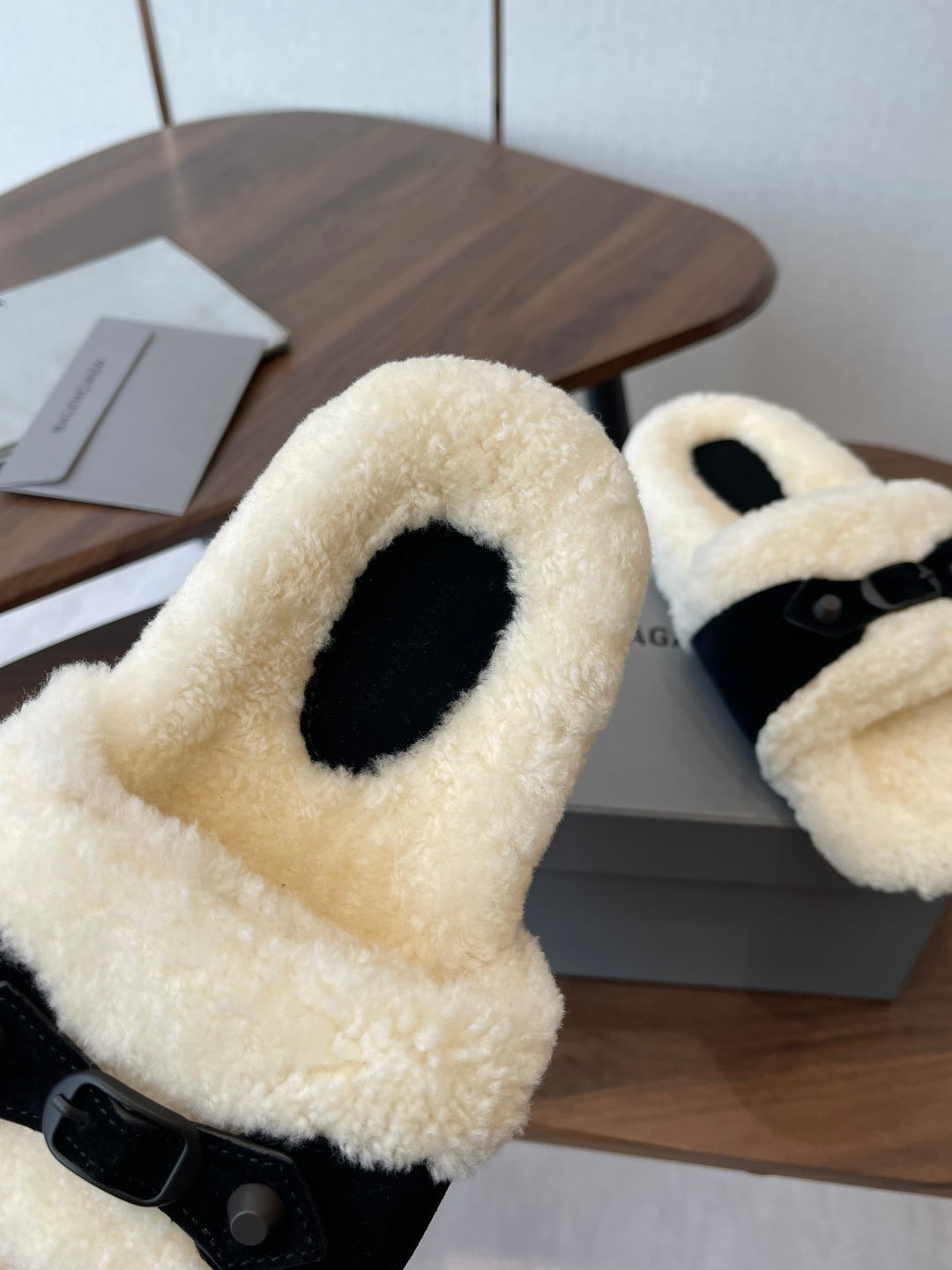 Balenciaga fuzzy slide sandal with cream shearling strap and black base, close-up