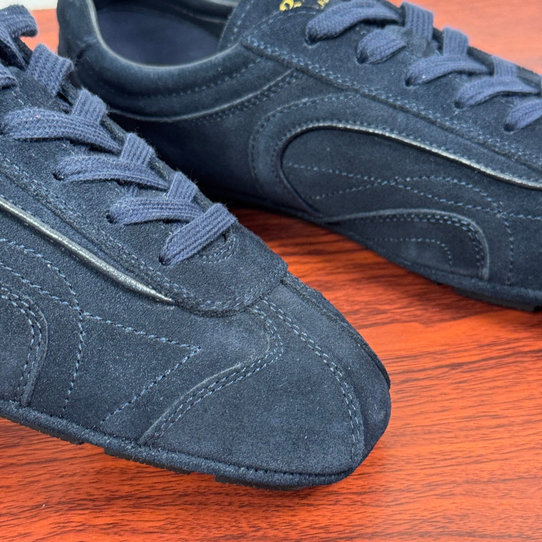 Navy suede Prada sneakers close-up, textured laces and stitched side logo
