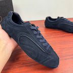 Navy suede Prada sneakers held in hand, lace-up front with side logo stripe