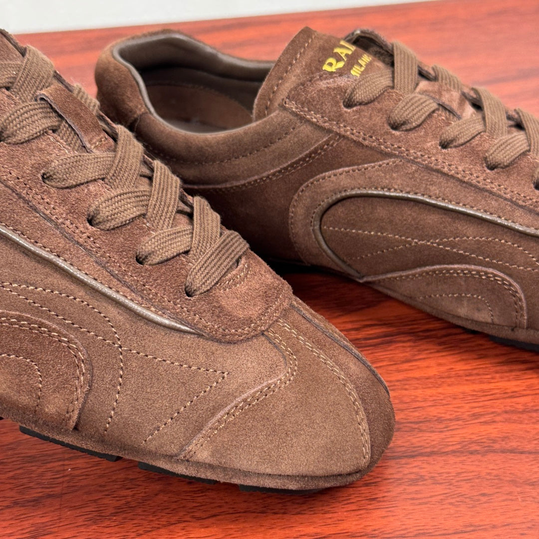 Brown suede sneakers close-up, lace-up front and side logo panel