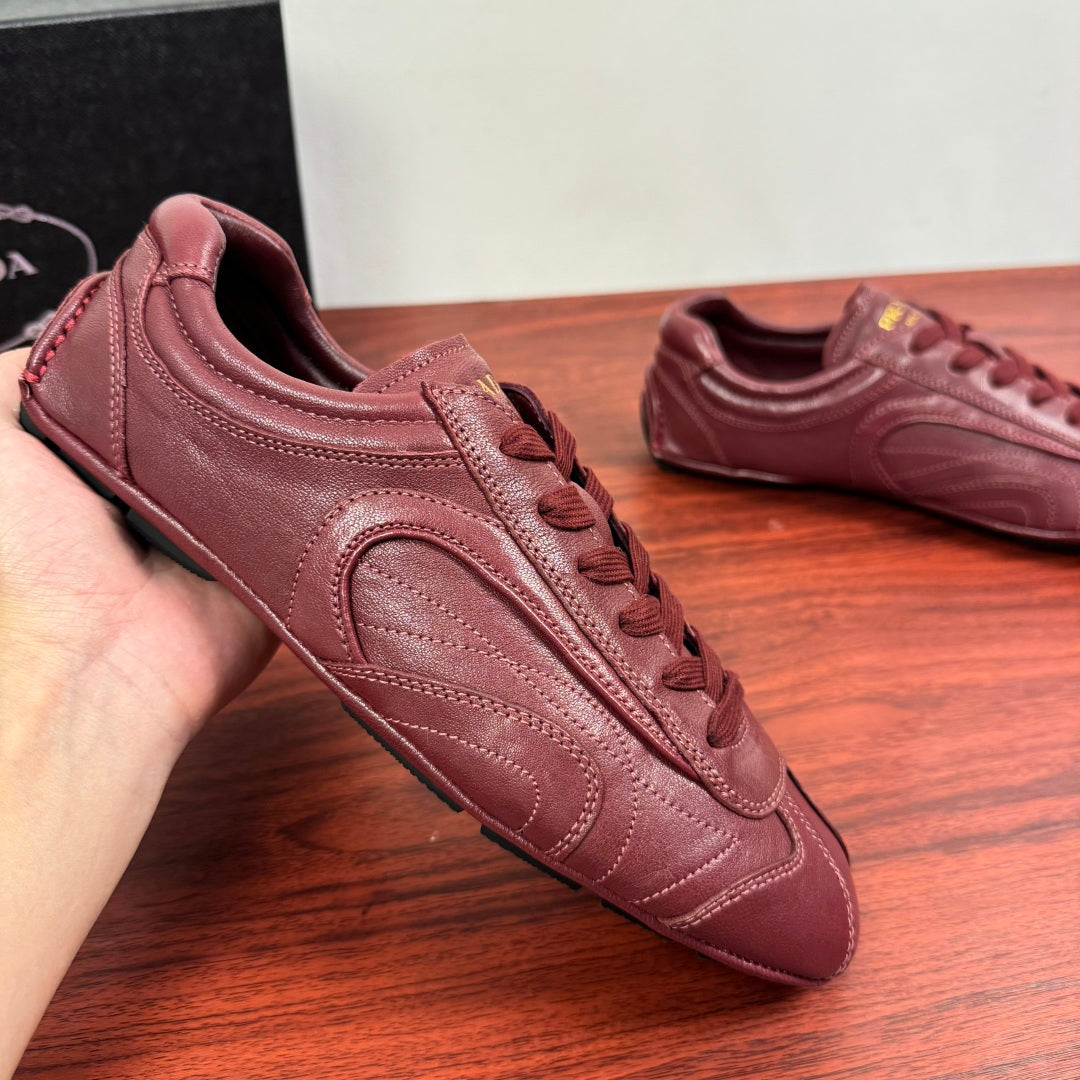 Prada unisex leather sneaker in burgundy, close side view with lace eyelets