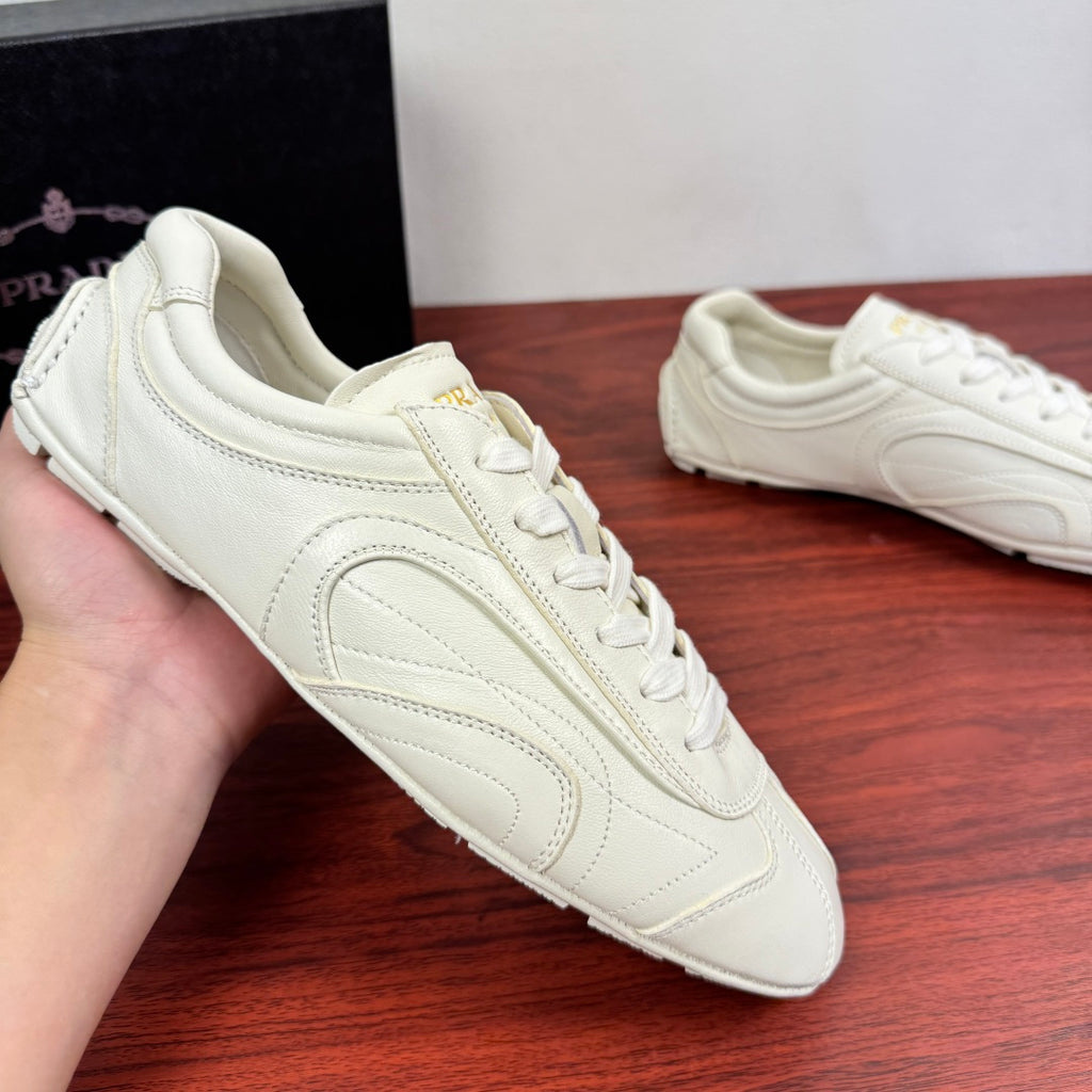 White leather lace-up sneakers held in hand, front-side view