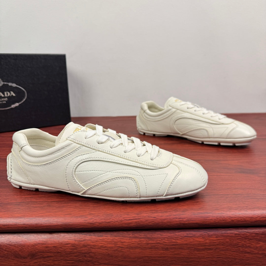 White leather lace-up sneakers with curved side seams and smooth toe cap