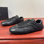Prada unisex sneakers pair, dark leather, front quarter view with lace-up laces