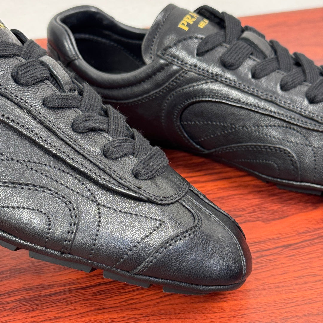 Prada unisex sneakers, close-up of toe and laces, dark leather with stitch details