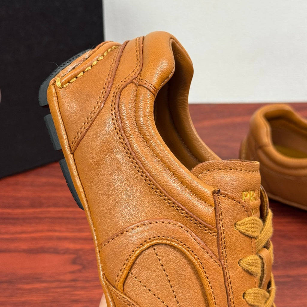 Tan leather sneaker close-up, showing padded collar and yellow lace-up eyelets