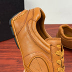 Tan leather sneaker close-up, showing padded collar and yellow lace-up eyelets