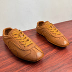 Tan Prada unisex sneakers shown from the side, with yellow lace-up ties
