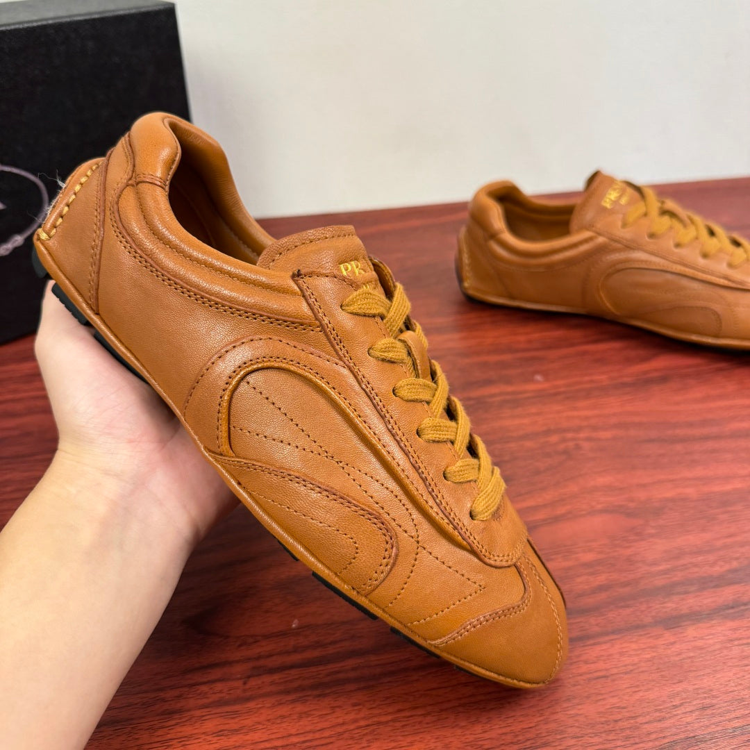Tan leather sneaker with yellow laces and side stripe stitching; left shoe close-up