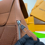 Close-up of taupe leather backpack zipper pull and textured side panel with strap.