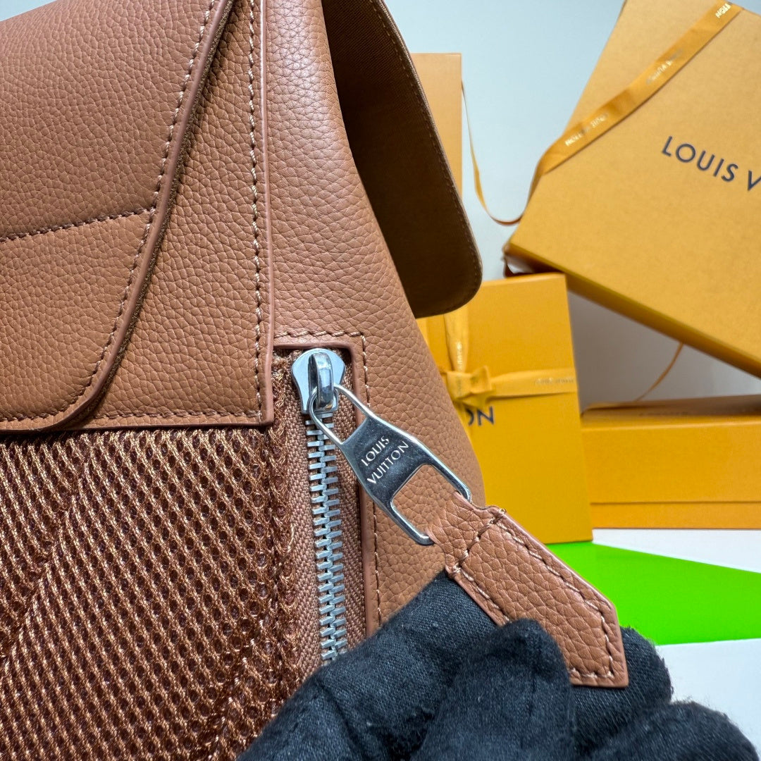 Close-up of taupe leather backpack zipper pull and textured side panel with strap.