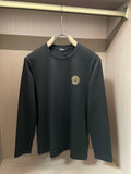 Black long-sleeve crewneck shirt with gold Medusa-style emblem on chest