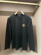 Black long-sleeve crewneck shirt with gold Medusa-style emblem on chest