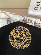 Black shirt with gold circular Medusa-style emblem applique
