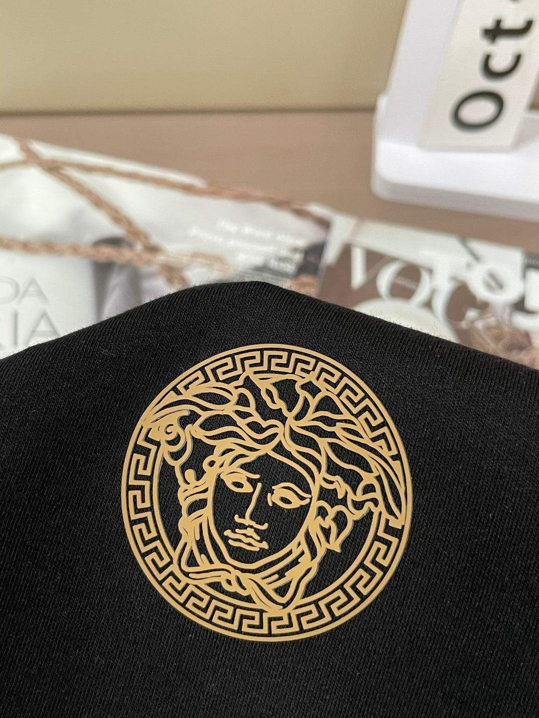 Black shirt with gold circular Medusa-style emblem applique
