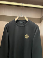 Black long-sleeve crewneck shirt with chest logo patch and small neckline tag