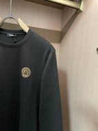Black long-sleeve crewneck shirt with gold emblem close-up on left chest