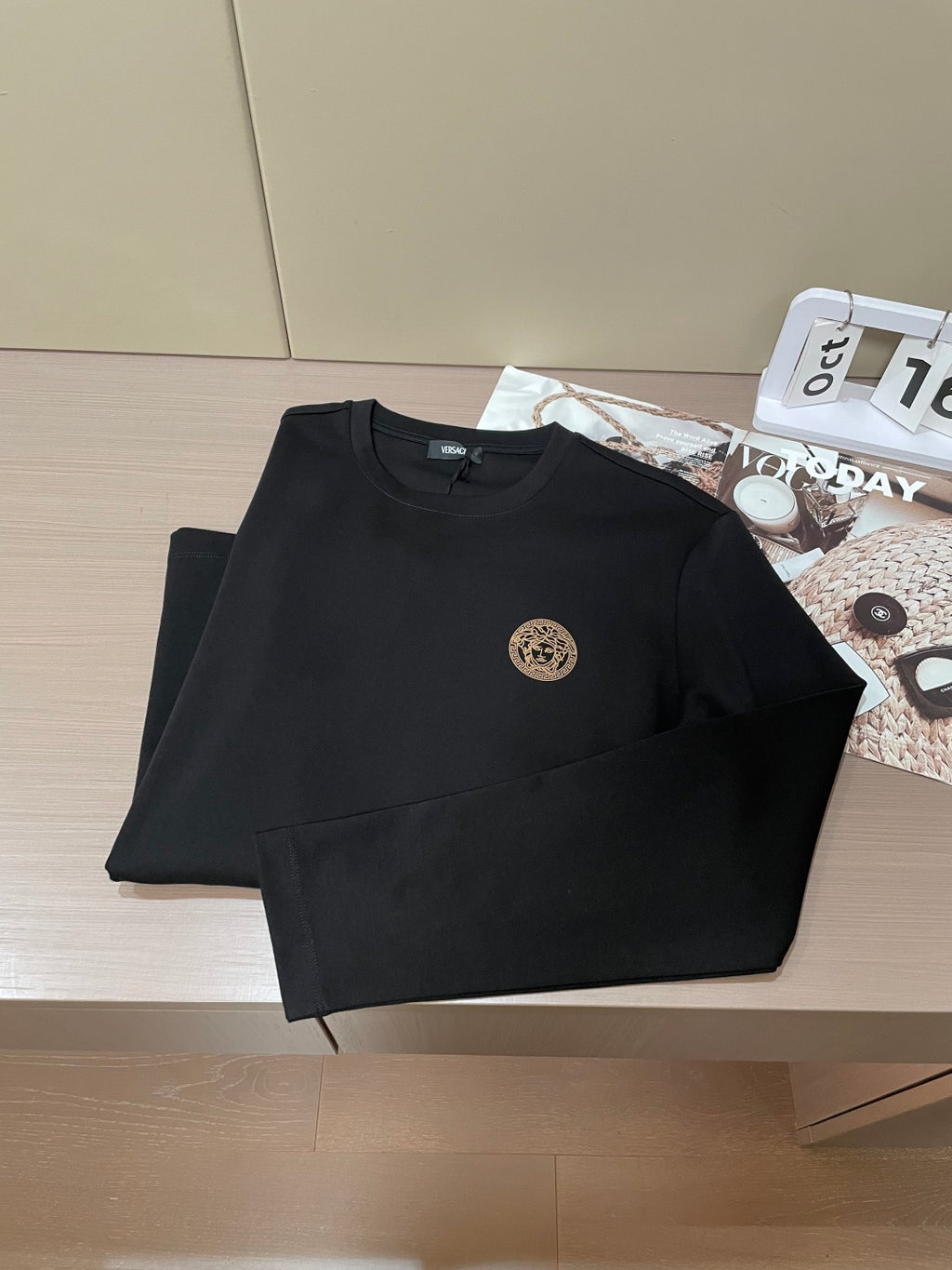 Black folded long-sleeve crewneck shirts with gold chest emblem