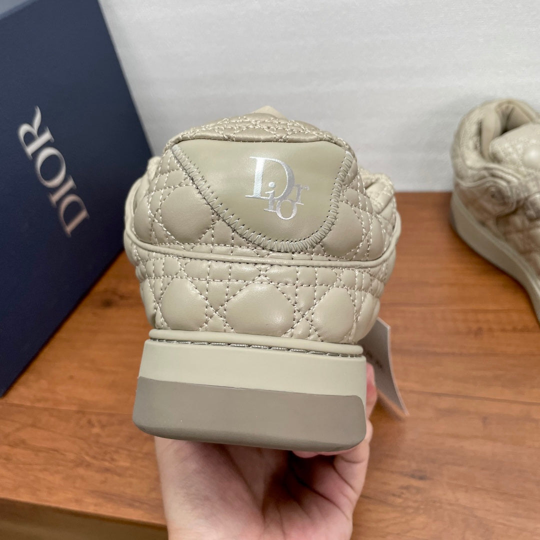 Back view of beige quilted sneakers with embroidered D logo on the heel