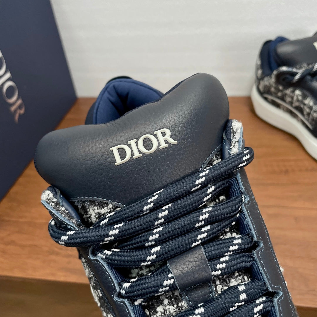 Dior high-top sneaker detail with navy tongue, silver pattern, and blue laces