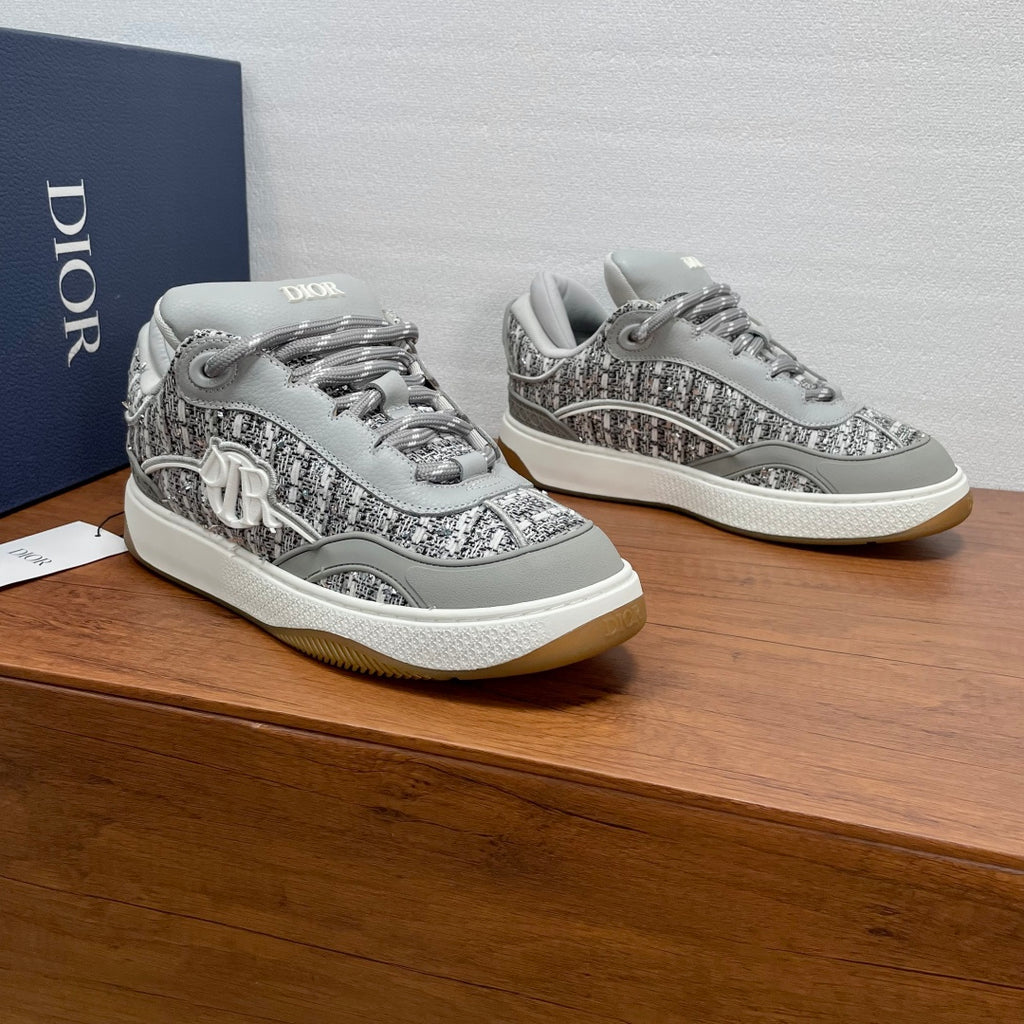Light gray low-top sneakers with speckled texture, lace-up, and Dior side emblem