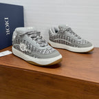 Light gray low-top sneakers with speckled texture, lace-up, and Dior side emblem