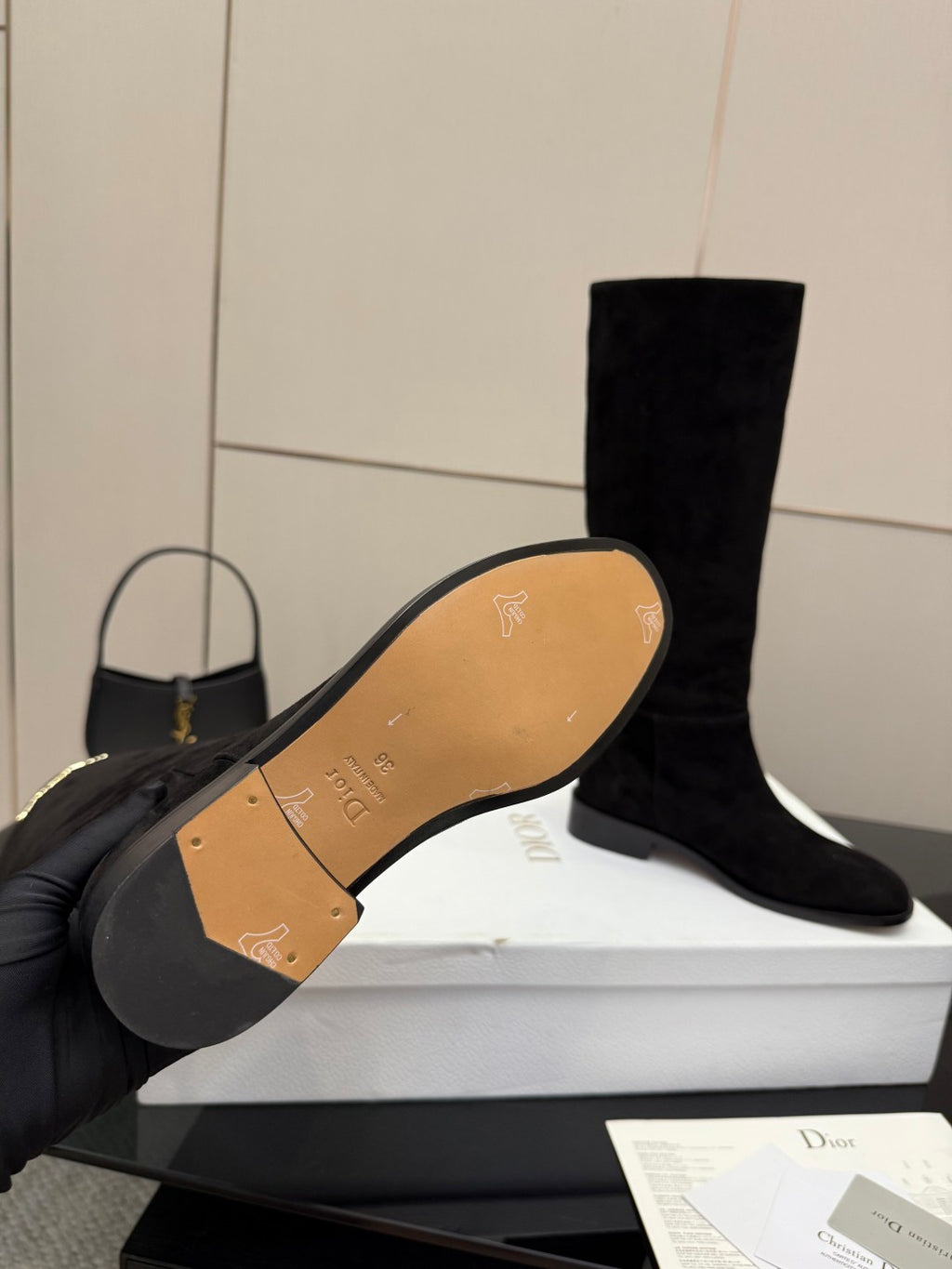 Knee-high suede boots with tan outsole underside showing branding and arrow symbols