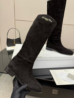 Black knee-high suede boots close-up with logo patch on upper shaft