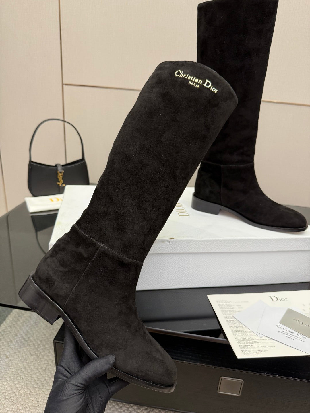 Black knee-high suede boots close-up with logo patch on upper shaft