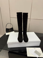 Knee-high suede boots in black on a white box, rounded toe, block heel