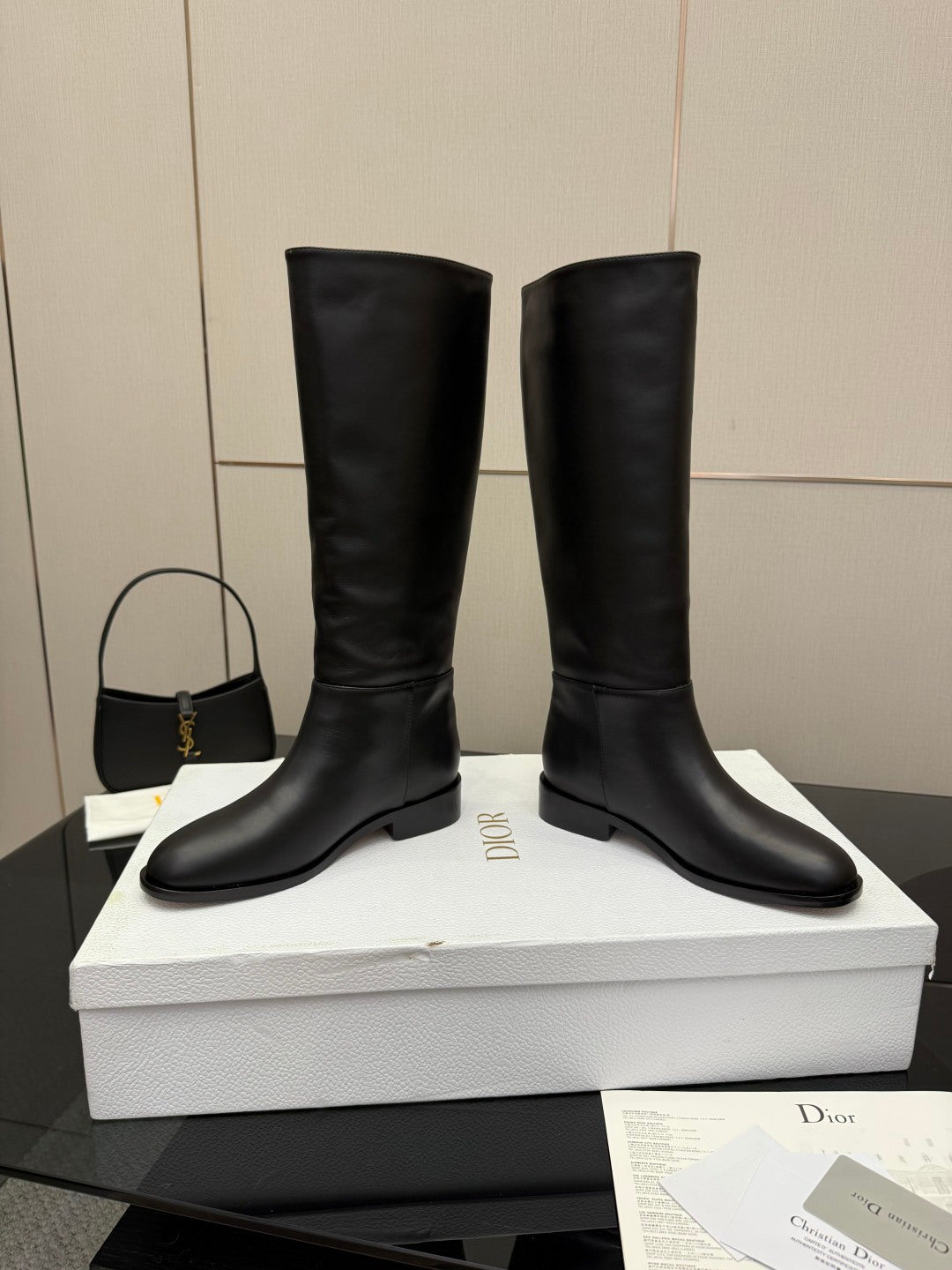 Black leather knee-high boots with low heel, stacked on shoebox