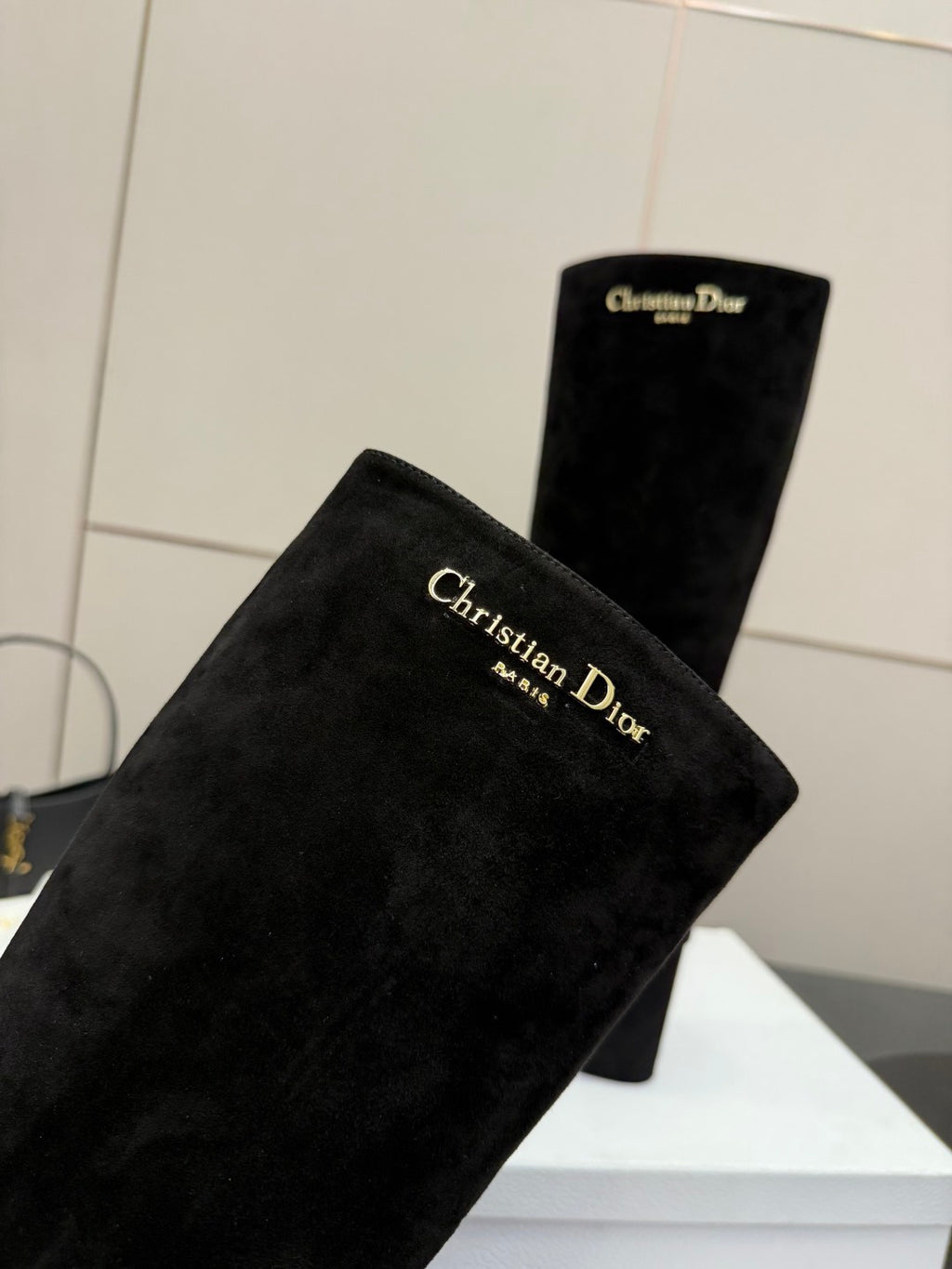 Black knee-high suede boots with high shafts and chunky heels, angled close-up