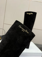 Black knee-high suede boots with high shafts and chunky heels, angled close-up