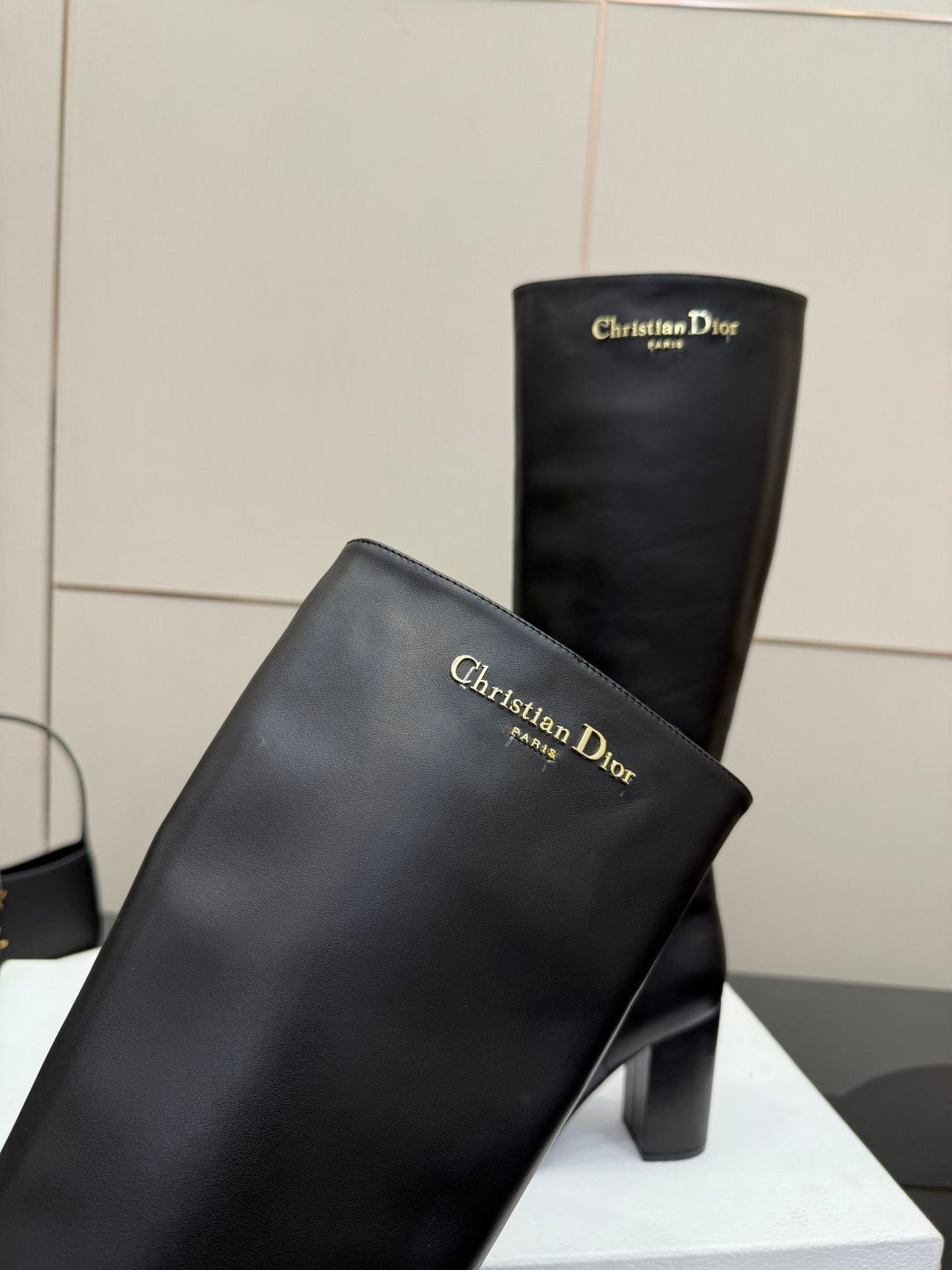 Close-up of black knee-high boot with block heel and Dior logo on upper