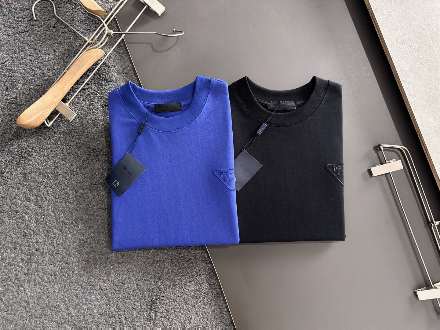 Prada long-sleeve tops, blue and black, on display hangers