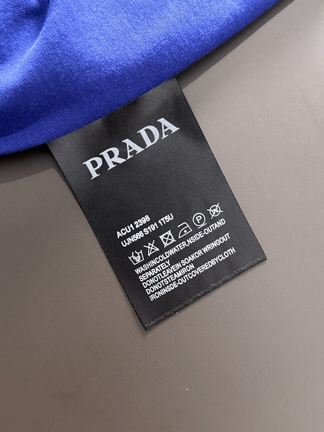 Prada clothing care label tag on blue long-sleeve top