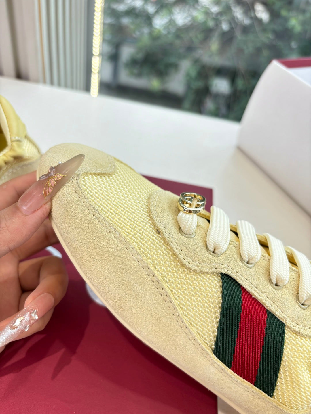 Women's yellow sneaker side close-up with gold logo lace hardware and Web stripe