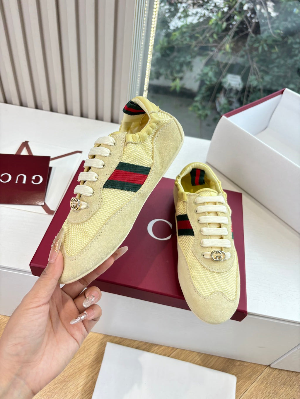 Women's yellow low-top sneakers, hand holding shoe with Web stripe detail