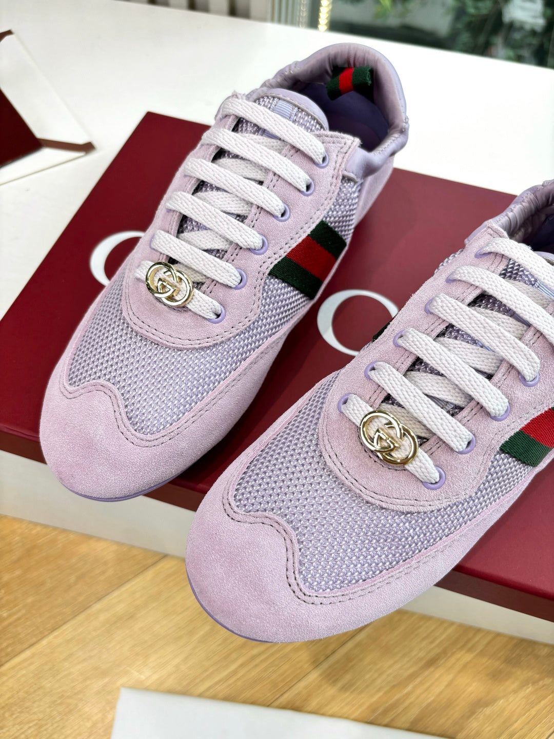 Lilac Gucci ladies sneakers close-up, gold crest, green-red side stripe, white laces