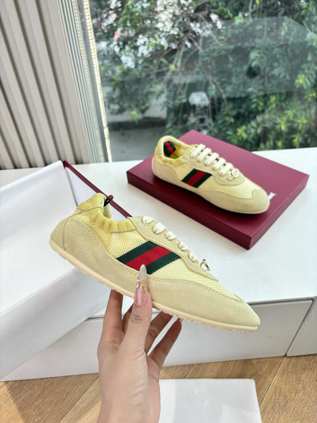 Women's yellow low-top sneaker on box, hand-held side with Web stripe