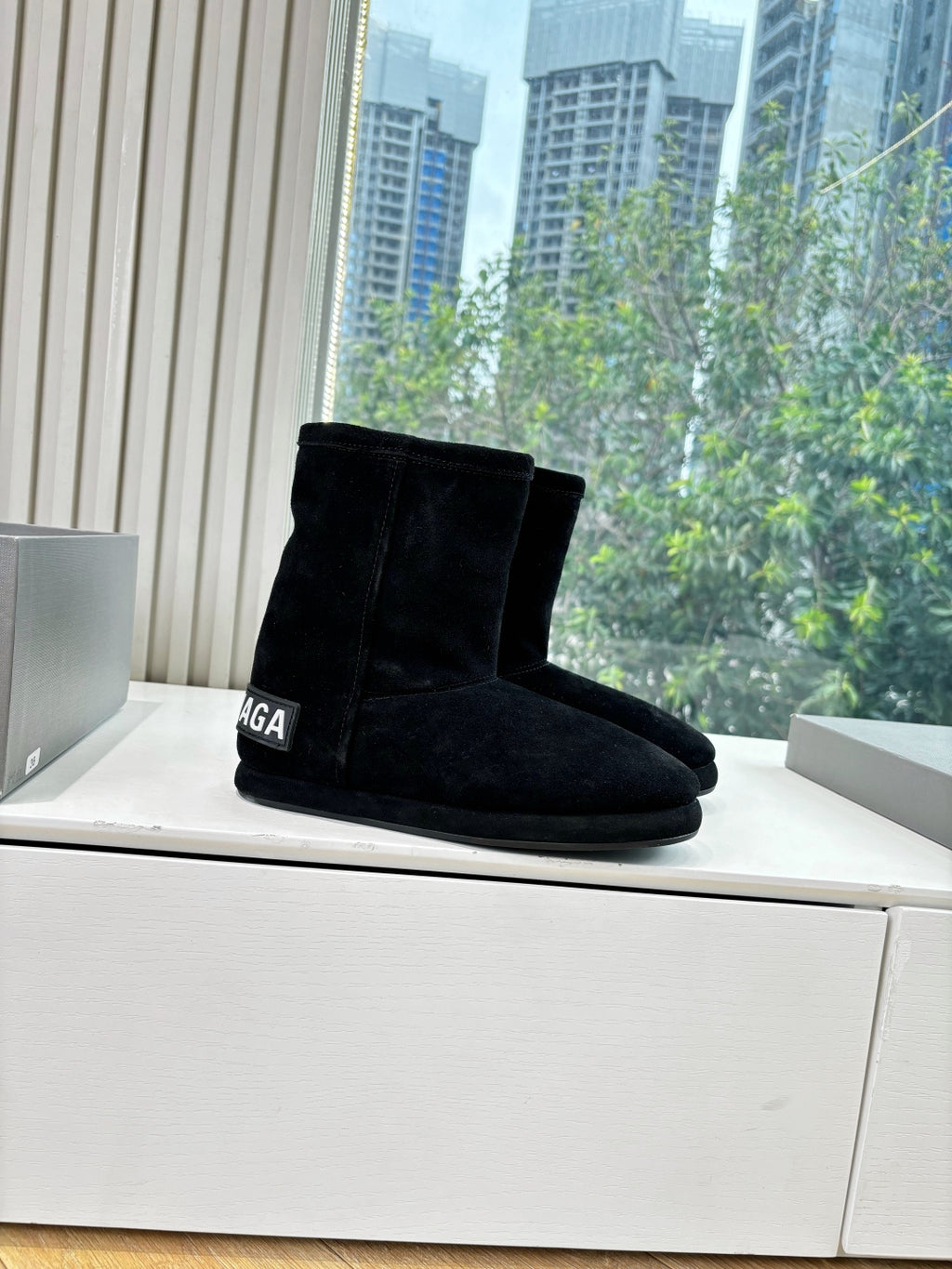 Black suede ankle boots with low heel, side logo detail, angled view
